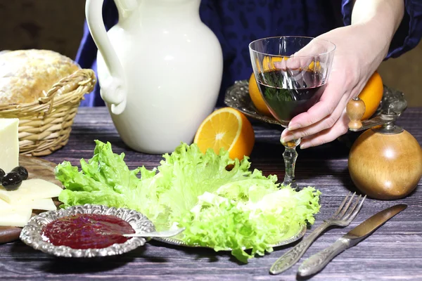 Female hands put on a table a glass with red wine — Stock Photo, Image