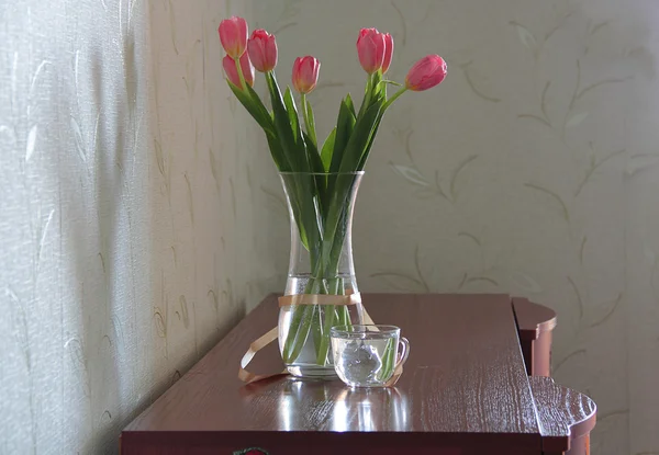Rosa Tulpen in einer transparenten Vase auf einer Holzkommode — Stockfoto