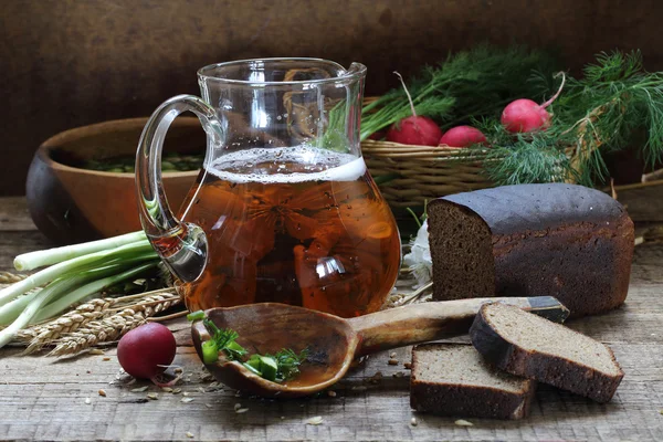 Karaf met kvas en roggebrood op een houten tafel — Stockfoto