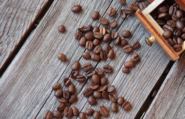 Granos de café y molino manual sobre una mesa de madera — Foto de Stock