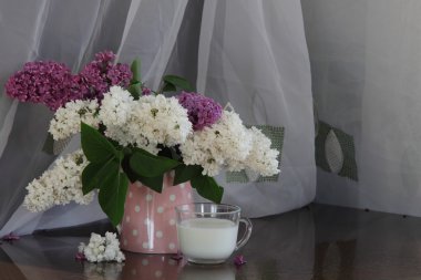 Şeffaf bir sürahi ve bir bardak süt ile Lila buket