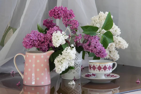 透かし花瓶と紅茶のカップでライラックの花束 — ストック写真