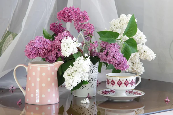 Bouquet de lilas dans un vase ajouré et une tasse de thé — Photo