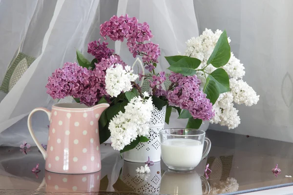 Bouquet de lilas dans une cruche transparente et une tasse de lait — Photo