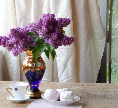 Bir zephyr, bir fincan çay ve Lila bir buket ile natürmort