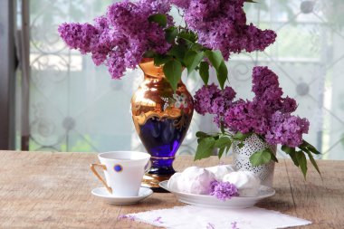 Bir zephyr, bir fincan çay ve Lila bir buket ile natürmort