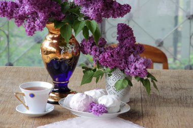 Bir zephyr, bir fincan çay ve Lila bir buket ile natürmort