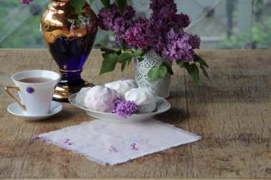 Bir zephyr, bir fincan çay ve Lila bir buket ile natürmort