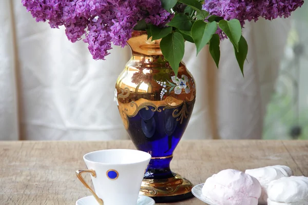 Bodegón con un zephyr, una taza de té y un ramo de lila en un — Foto de Stock