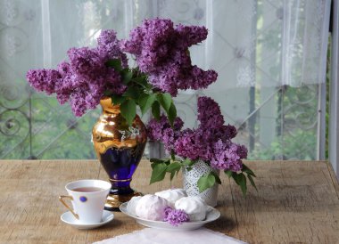 Bir zephyr, bir fincan çay ve Lila bir buket ile natürmort
