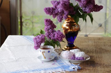 Bir zephyr, bir fincan çay ve Lila bir buket ile natürmort