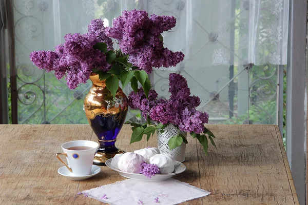 Té en una taza de porcelana, un zephyr y un ramo de lila en un beauti — Foto de Stock