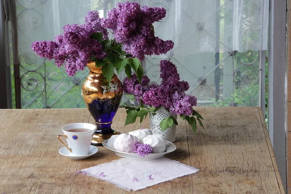 Té en una taza de porcelana, un zephyr y un ramo de lila en un beauti — Foto de Stock