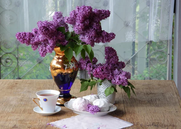 Bodegón con un zephyr, una taza de té y un ramo de lila en un — Foto de Stock