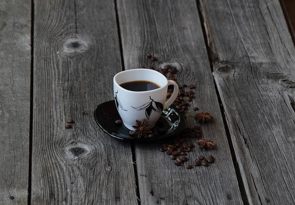 Coffee in a coffee cup in an environment of coffee grains and an — Stock Photo, Image
