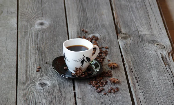 Coffee in a coffee cup in an environment of coffee grains and an — Stock Photo, Image