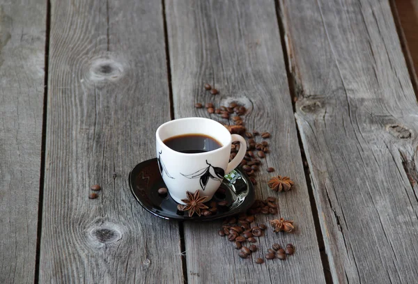 Coffee in a coffee cup in an environment of coffee grains and an — Stock Photo, Image