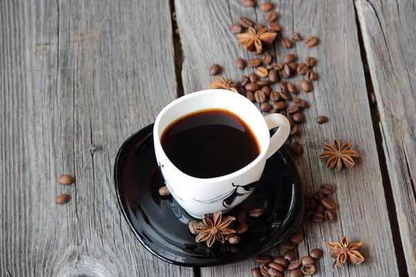 Coffee in a coffee cup in an environment of coffee grains and an — Stock Photo, Image