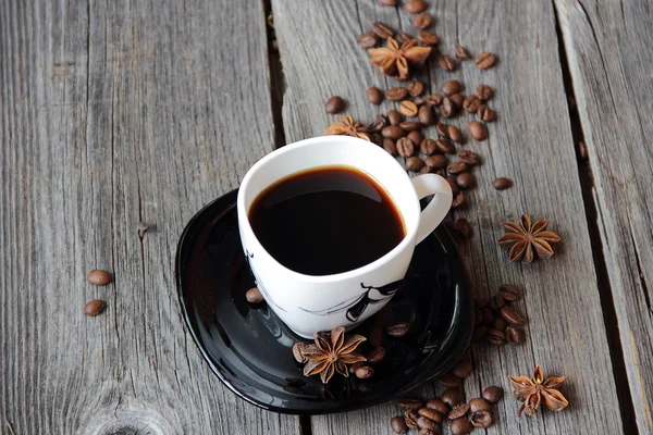 Coffee in a coffee cup in an environment of coffee grains and an — Stock Photo, Image