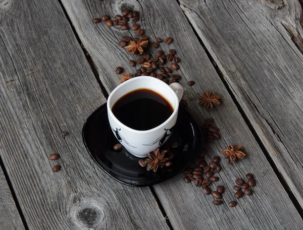 Coffee in a coffee cup in an environment of coffee grains and an — Stock Photo, Image