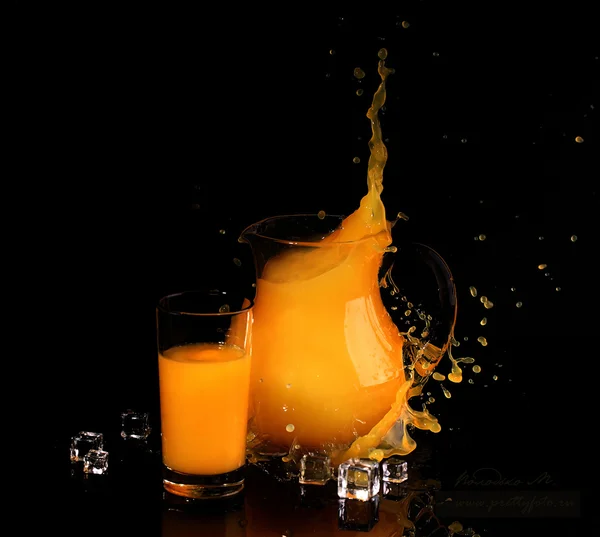 Splash w sok pomarańczowy przezroczysty dzban na czarny deseń — Zdjęcie stockowe