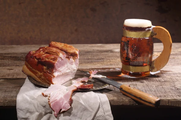 Beer with foam in a transparent mug and smoked meat with a fat l — Stock Photo, Image