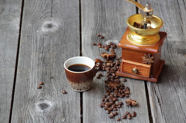 Xícara de café e moedor de café manual em um fundo de madeira — Fotografia de Stock