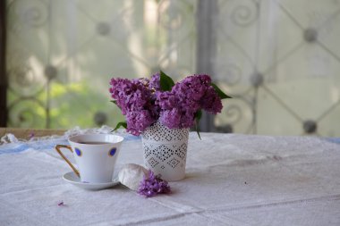 Çay, bir zephyr ve Lila bir buket ile natürmort