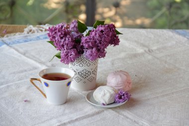 Çay, bir zephyr ve Lila bir buket ile natürmort