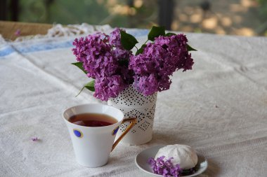 Çay, bir zephyr ve Lila bir buket ile natürmort