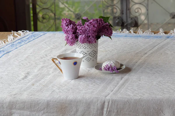 Té con un zephyr y un ramo de lila en un hermoso jarrón — Foto de Stock