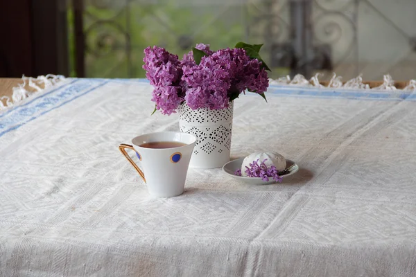 Té con un zephyr y un ramo de lila en un hermoso jarrón — Foto de Stock