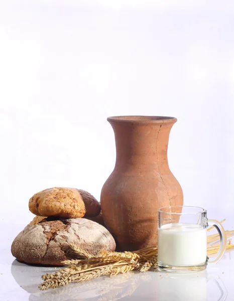 Milk in a transparent mug and fresh bread on a white background — Stock Photo, Image