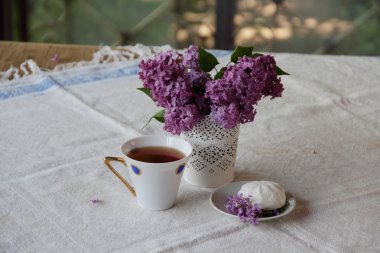 Bir leylak, Zephyr'i ve güzel bir fincan çay ile natürmort