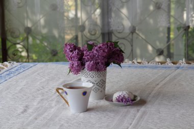 bir fincan çay, bir zephyr ve Lila bir buket ile natürmort