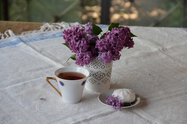 Bodegón con una lila, un zephyr y té en una hermosa taza — Foto de Stock