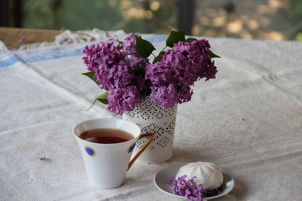 Bodegón con una lila, un zephyr y té en una hermosa taza — Foto de Stock
