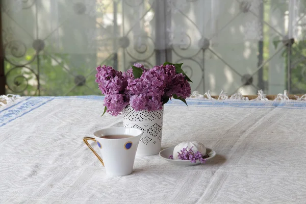 Té en una taza hermosa, un zephyr y un ramo de lila — Foto de Stock