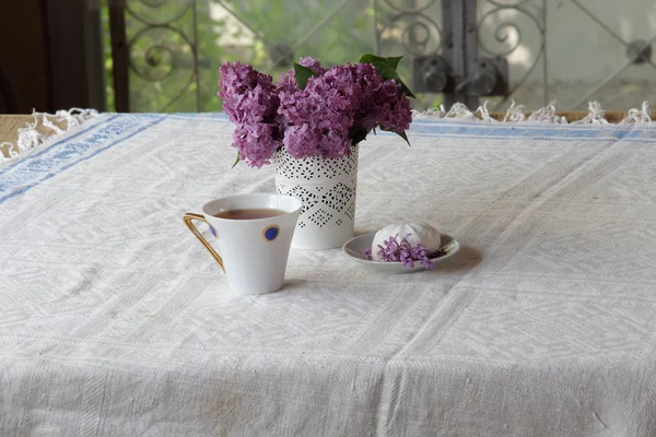 Stillleben mit einer Tasse Tee, einem Zephyr und einem Fliederstrauß — Stockfoto