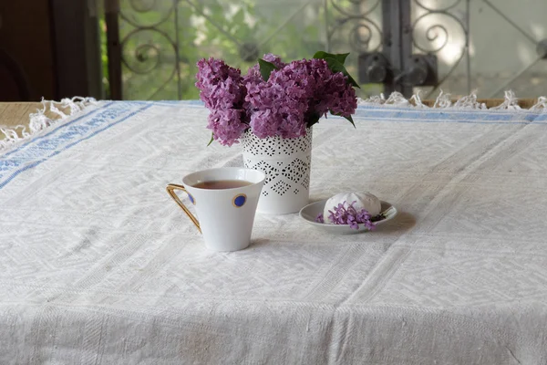 Té en una taza hermosa, un zephyr y un ramo de lila — Foto de Stock