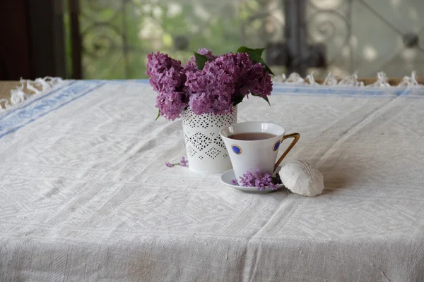 Stillleben mit einer Tasse Tee, einem Zephyr und einem Fliederstrauß — Stockfoto