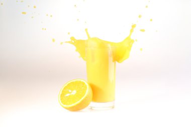 Splash in orange juice in a transparent glass on a white backgro
