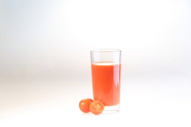 Beyaz arka planda şeffaf bir bardakta domates suyu.