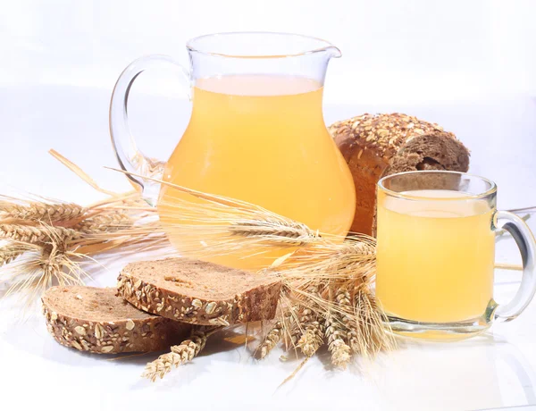 Kvas (Kvas) şeffaf bir kupa, bir sürahi ve çavdar ekmeği bir whit üzerinde