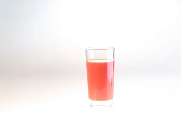 Jugo de tomate en un vaso transparente sobre fondo blanco — Foto de Stock