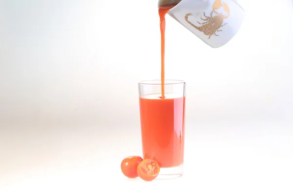 Suco de tomate um fluxo flui em um vidro transparente, um copo de t — Fotografia de Stock