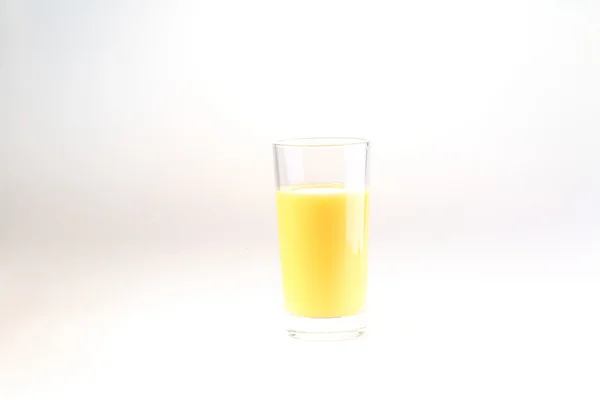 Orange juice in a transparent glass on a white background — Stock fotografie