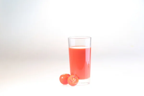 Sumo de tomate em um copo transparente em um fundo branco — Fotografia de Stock
