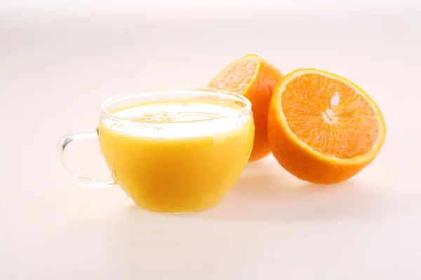 Orange juice in a transparent cup and halves of a juicy ripe ora — Zdjęcie stockowe