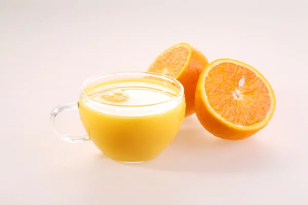 Orange juice in a transparent cup and halves of a juicy ripe ora — Zdjęcie stockowe